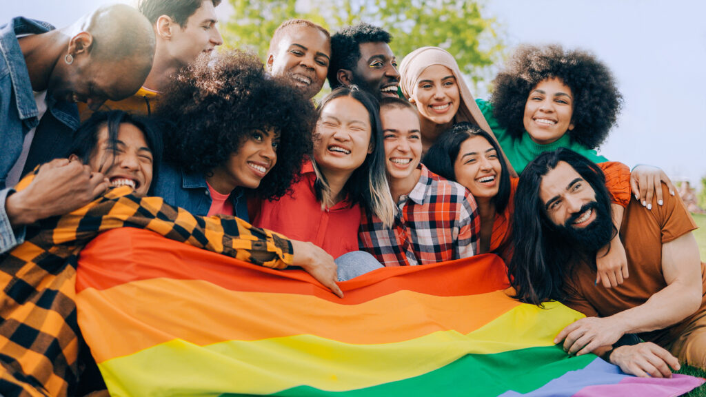 Happy diverse people holding lgbt rainbow flag outdoors