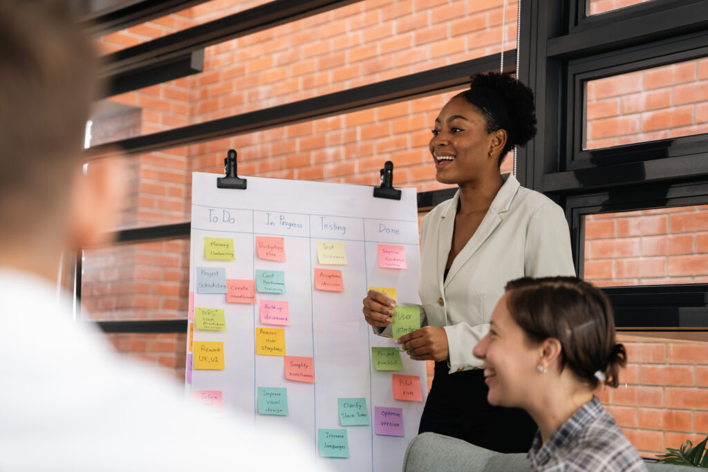 Diverse coworkers in a team group meeting with a board filled with sticky notes.