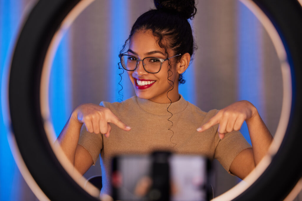 Shot of a young woman pointing down while using a phone to film at home