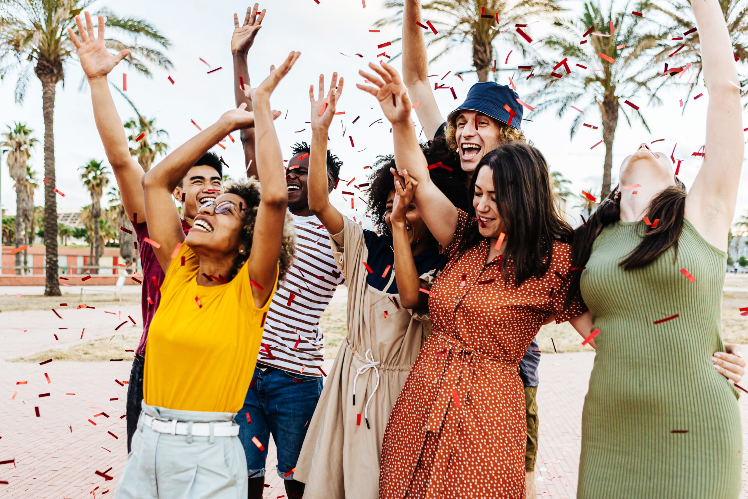 Happy friends throwing confetti and enjoying summer party outdoors