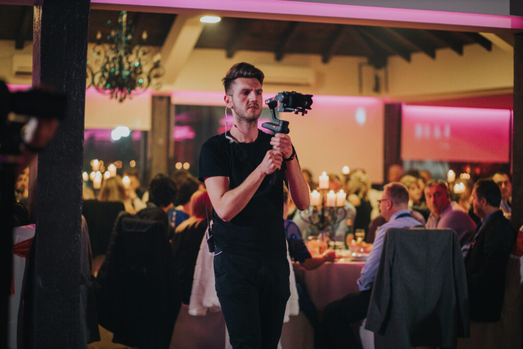 A young cameraman filming a wedding celebration in a restaurant.