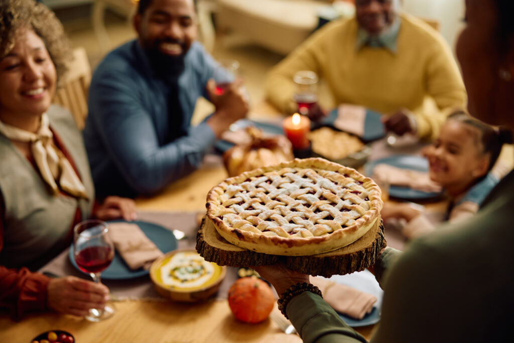 Close up of a mother serving sweet pie during family meal on Thanksgiving.