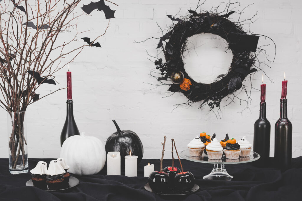 Halloween desserts and spooky decorations on table.