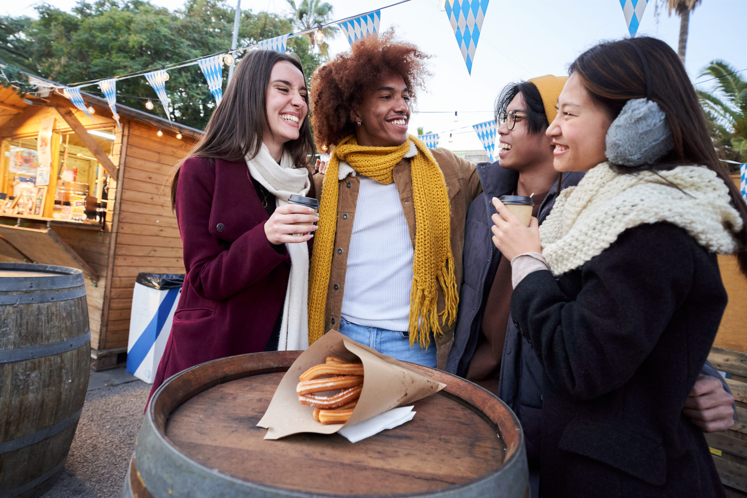 Happy smiling friends eating chocolate with churros together on the street outdoors.