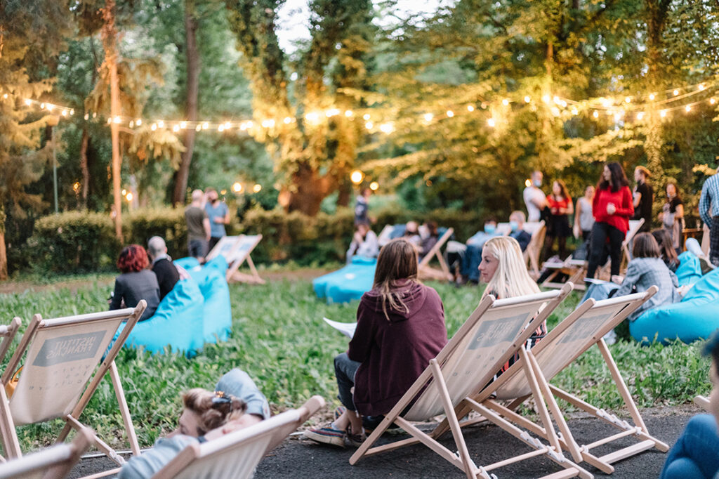 Outdoor venue space with people in lawn chairs and fairy lights in the trees.