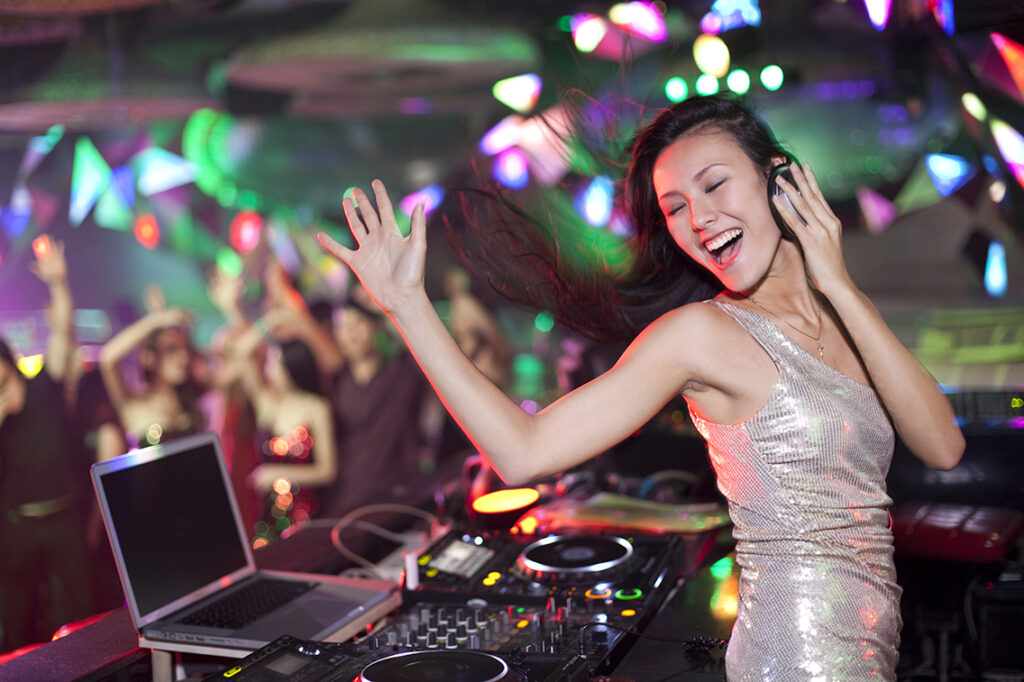 DJ at an event with dancing guests in the background.