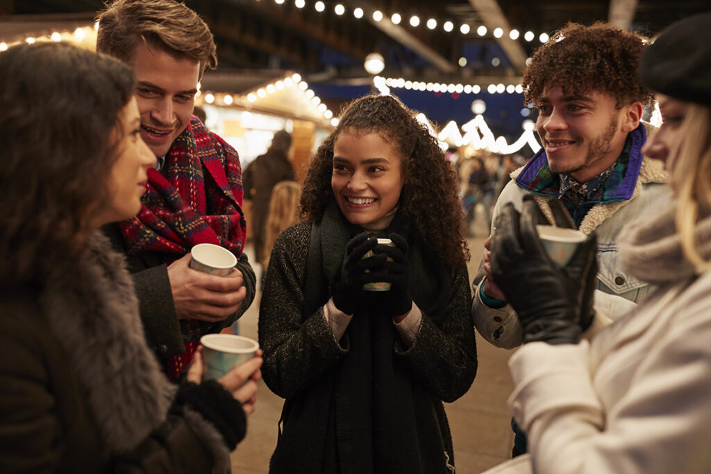 Group Of Friends Drinking Mulled Wine At Christmas Market