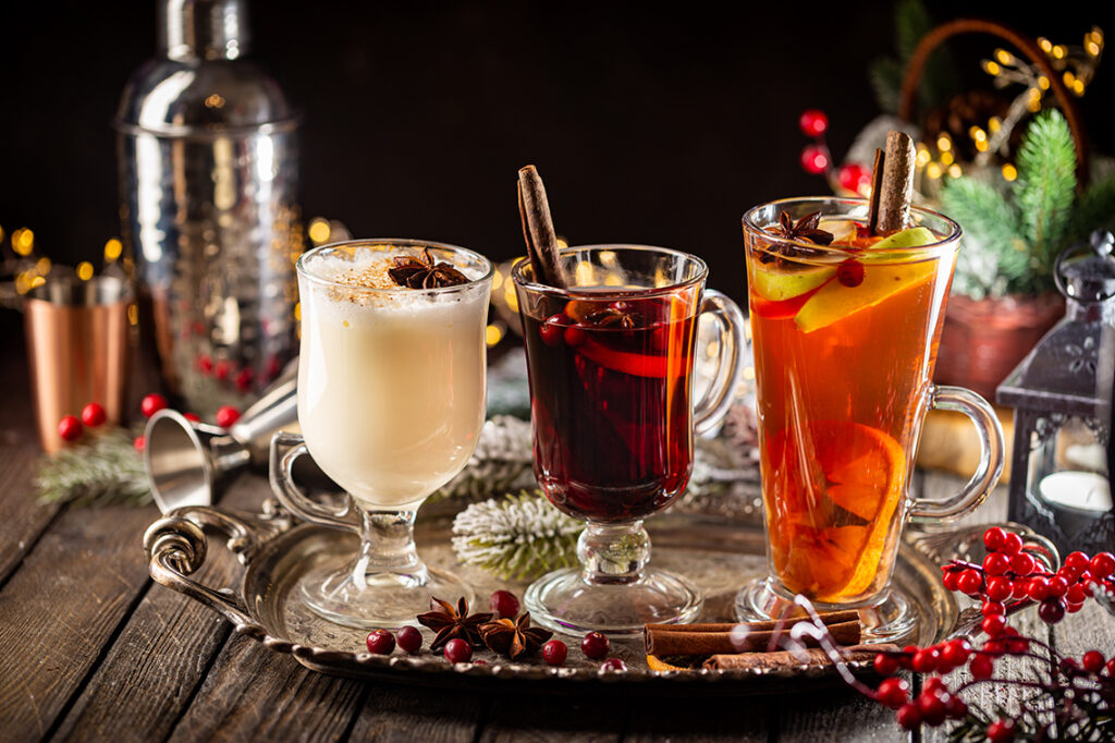 fresh eggnog, grog and fruity red mulled wine with Christmas decoration. Selection of autumn or winter alcoholic hot drinks